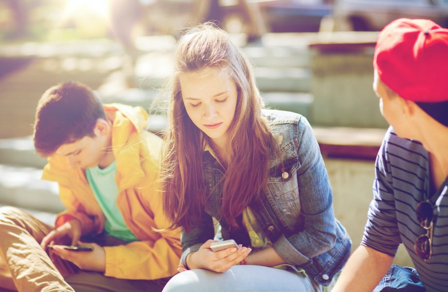 teenage friends with smartphones outdoors